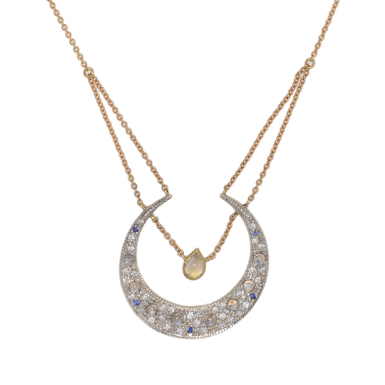 Selene Diamond Crescent Moon Necklace by Unhada. The Selene Diamond Moon Necklace is aptly named after the Greek goddess and features a sterling silver pendant encrusted with .34 cts of diamonds, complemented by blue sapphires and faceted rainbow moonstones. Adding to its elegance, a single pear-cut labradorite rests at the center of the crescent, suspended from an 18k yellow gold chain. The necklace can be adjusted to a length of 16 - 18" making it perfect for layering with other pieces.