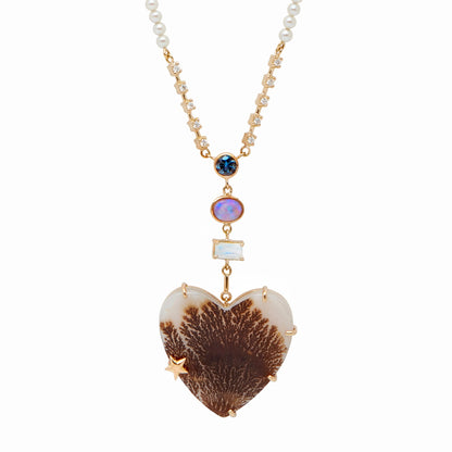 From the whimsical Fairydusted Collection, the Titania Heart Necklace embodies a playful elegance and a curated sense of charm. Featuring a heart-shaped agate at its center, the necklace is adorned with a magical scattering of moonstones (.62 cts), opals (17 cts), iolite (.23 cts), sapphires, pearls, and a sparkling diamond (.11 cts). Set on an adjustable 18k gold chain, it can be worn at lengths from 17" to 21".